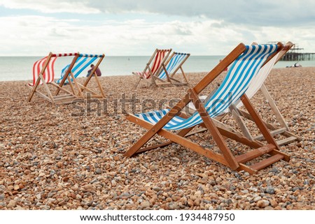 Pairs of empty red and blue striped hammocks available for hire on the beach in the southern UK town of Brigthon near the West Pier. Royalty-Free Stock Photo #1934487950