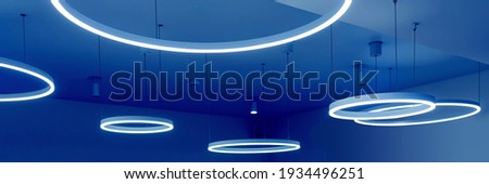 Ceiling with round modern LED lamps. Suspended fluorescent lights under the ceiling. Careful energy consumption, energy saving concept. Banner Royalty-Free Stock Photo #1934496251
