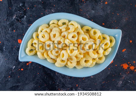 Sweet corn sticks in sky blue plate, on navy blue background with orange spots. High quality photo