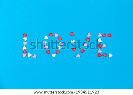 small white, pink and red hearts forming a word Love on blue background