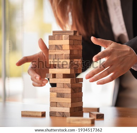 Abstract businesswomen fail danger tower block game building construction protect plan and project control.