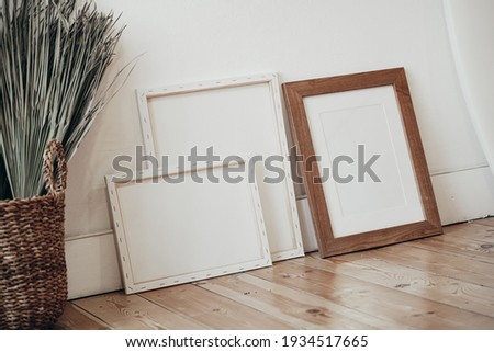 Square wooden frame mockup on vintage floor. Modern vase with dry Lagurus ovatus grass. White wall background. Scandinavian interior. White Surfboard