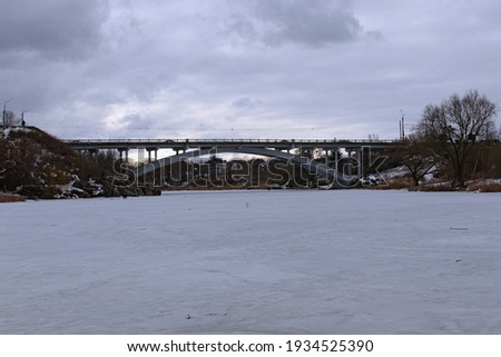Bridge over Ros River in Bila Tserkva. Winter landscape view of frozen river in cloudy day. Bila Tserkva, Ukraine.