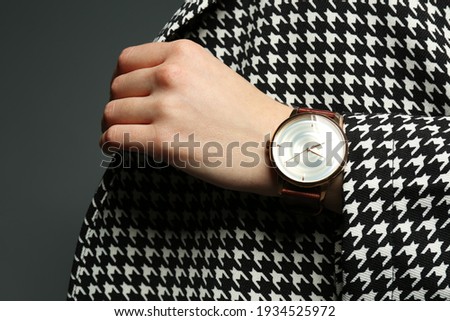Woman wearing luxury wristwatch on grey background, closeup