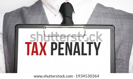 Businessman holding sheet of paper with a message TAX PENALTY