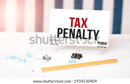TAX PENALTY sign on paper on white desk with office tools. Blue and white background