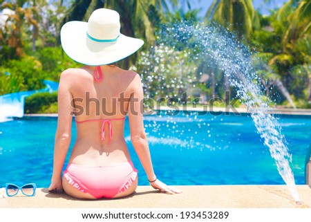 back view o fa  woman in straw hat relaxing by the pool