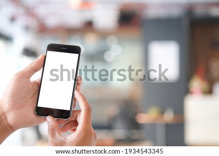 Mock up smartphone of hand holding black mobile phone with blank white screen.