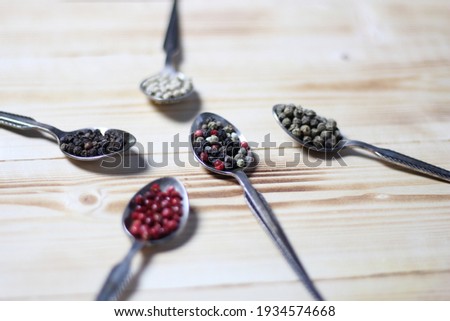 Four pepers seasoning of white pepper, green, black, Pink peppercorn in metal spoons on wooden background