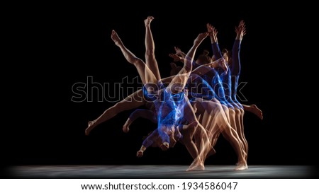 Glowing. Young flexible girl on black studio background in strobe, neon light. Fit female model practicing artistic gymnastics. Exercises for flexibility, balance. Grace in motion, sport, action.