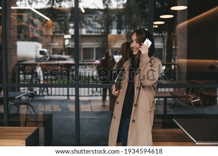 business confident successful freelancer adult female blogger works using technology laptop phone communicates at work school with friends on the street next to a cafe in front of a storefront window