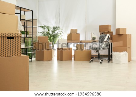 Cardboard boxes and packed chair in office. Moving day Royalty-Free Stock Photo #1934596580