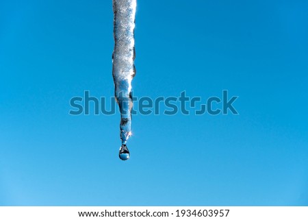 Icicles melt and drip in the spring against the blue sky.Meteorology, global warming, and melting snow and ice. Water dripping against the sky. Royalty-Free Stock Photo #1934603957