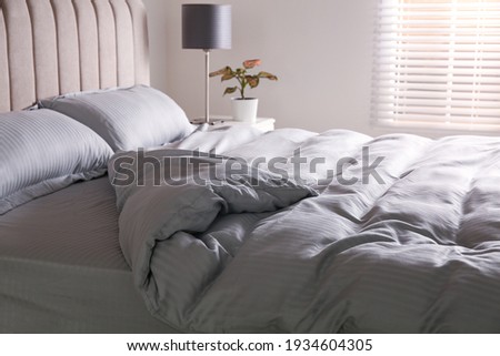 Comfortable bed with soft blanket near window indoors Royalty-Free Stock Photo #1934604305