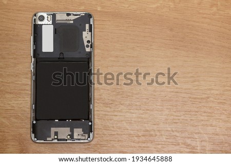 Smartphone with the back cover removed on the table. Concept of gadget repair.