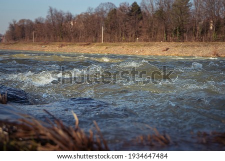 Water texture. Mountain river on the background of the city. Waves of green, blue and gray. Calm and tranquility. River shore. Rapid flow of water, photo of the surface of the river