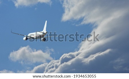 Zoom photo of passenger airplane taking off reaching altitude above clouds in deep blue sky