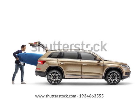 Man putting a surfboard in the trunk of a SUV isolated on white background Royalty-Free Stock Photo #1934663555