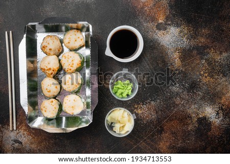 Sushi rolls in takeaway container set, on old dark rustic background, top view flat lay , with copyspace and space for text