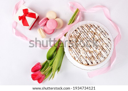 Cake with chocolate and meringue, marshmallow and flowers on a light table, festive food for mother's day, wedding, birthday. Modern bakery concept, advertising space, selective focus