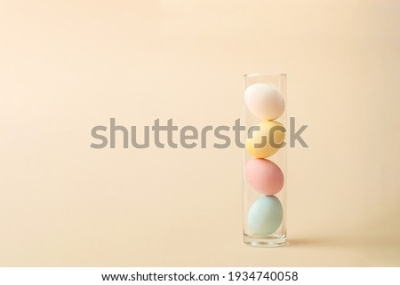 Pastel easter eggs in vase on beige background. Minimal zig zag arrangement with copy space.