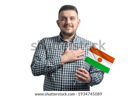 White guy holding a flag of Niger and holds his hand on his heart isolated on a white background With love to Niger.