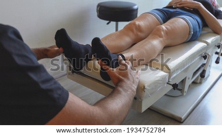 Osteopath holding feet of female patient lying on stretcher. Chiropractic manipulation, doctor office, medical examination concepts Royalty-Free Stock Photo #1934752784