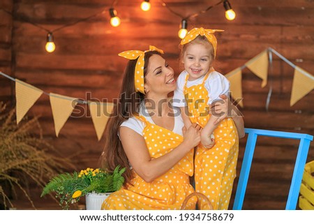 Close up Cheerful mother and child fooling, playing at Easter day. Woman, toddler girl dressed in yellow clothes, having fun at home. Family celebrating spring holliday together. Holy Week activities