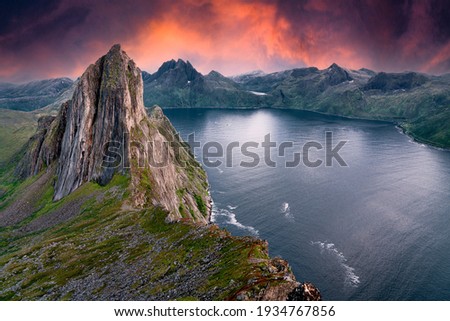 Segla Mountain from a nearby peak during sunset. The sky turned bright red orange and purple to give this image a dramatic variation to typical Norwegian landscapes. Heston Hike Royalty-Free Stock Photo #1934767856
