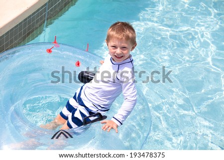 Happy little boy floating on a tube 