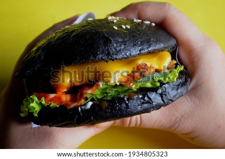 Cropped view of hand with homemade burger on black 