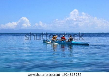 Men rowing a traditional outrigger canoe in French Polynesia Royalty-Free Stock Photo #1934818952