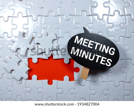 Wooden board with text MEETING MINUTES on puzzle background.Business concept. Royalty-Free Stock Photo #1934827004