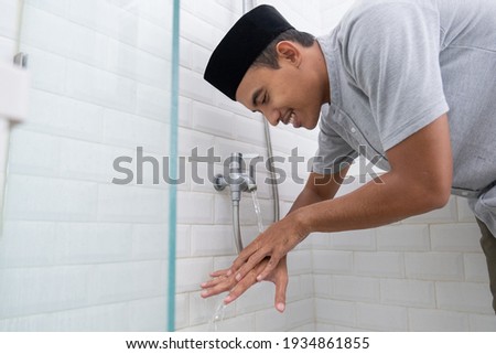 Young Muslim man perform ablution wudhu before prayer at home Royalty-Free Stock Photo #1934861855