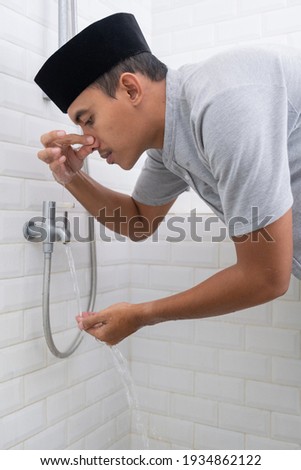 Young Muslim man perform ablution wudhu before prayer at home Royalty-Free Stock Photo #1934862122