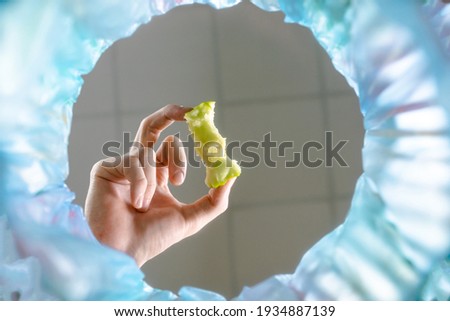 Hand throwing stub apple trash bin. Bottom view blue background copy space for designers