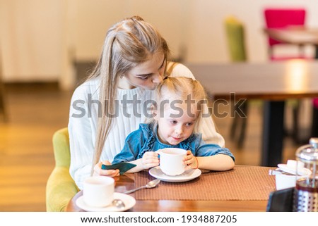 Mom and daughter eat in a cafe. Mom helps the child to eat .