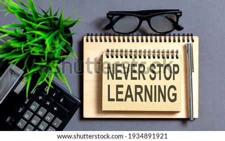 Notebook with Text never stop learning and calculator on grey table,