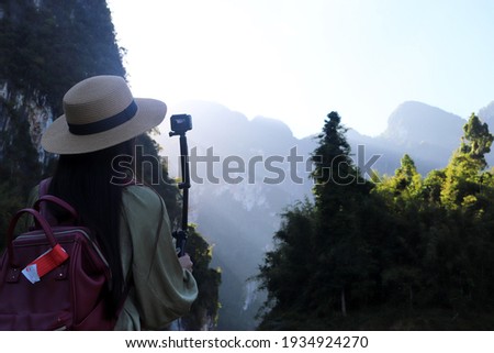 Woman traveler standing to take a photo with scenery view of the mountains and sunray in the morning natural background. Concept of light and shadow