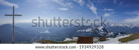 Panoramic view with a wooden christian cross and and the snowy mountain ranges of the Central and Bernese Alps in the Lake Lucerne area, Switzerland.