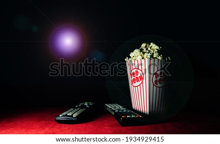 Pop corn and remote control in the home theater room.Selective focus Lettering, Popcorn.  