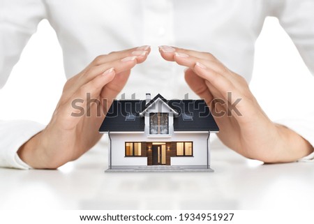 Home protection concept, close up of female hands sheltering modern house Royalty-Free Stock Photo #1934951927