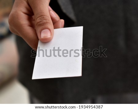 a woman's hand holding out a white card. mockup photo
