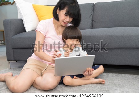 young asian mother and son sitting on sofa taking a selfie with digital tablet happy and smiling.
