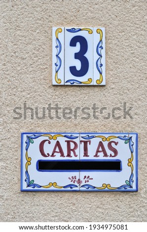 Colourful Ceramic Sign and Letter Plate Translated as 'Letters' on Textured Wall