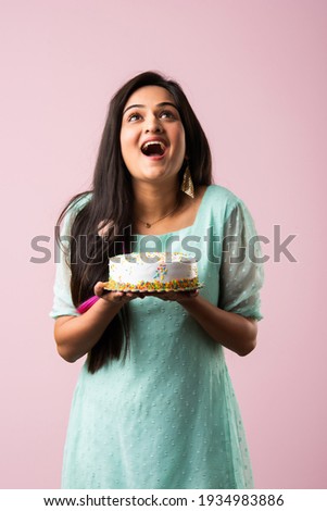 Pretty Indian asian young woman or girl holding birthday cake against pink background
