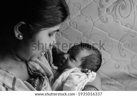Close up face of a cute newborn baby boy making funny face in her mother lap. One month old Sweet little infant toddler. Indian ethnicity. Front view. Happy mother’s day background image.