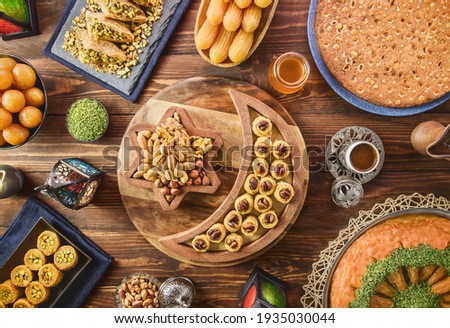 Arabic Cuisine: Middle Eastern desserts. Delicious collection of Ramadan traditional desserts. Served with tasty nuts, Arabic coffee, honey syrup and sugar syrup .Top view with close up. Royalty-Free Stock Photo #1935030044