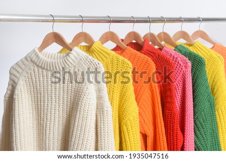 Row of different colorful Knitted, sweaters hang on hangers