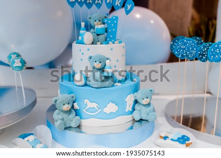 Candy bar. Baby birthday theme with teddy bear. Festive background decoration with cake, letters saying one and white blue balloons in studio.